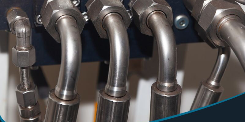 post-1-2 Marmon Keystone Close-up view of metal hydraulic tubes connected to fittings, highlighting Marmon/Keystone as your trusted metals distributor for JIC hydraulic tubing—welded J525 A214—available in stock and ready to ship for your supplychain needs.