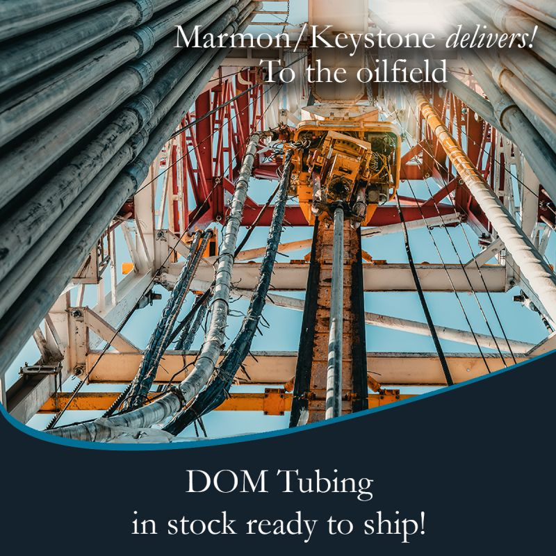 post-1-4 Marmon Keystone View looking up at steel pipes and equipment on an oil drilling rig, with text promoting Marmon/Keystone as your trusted metals distributorâwith DOM tube and pipe in stock and ready to ship for oilfield supply chain needs.